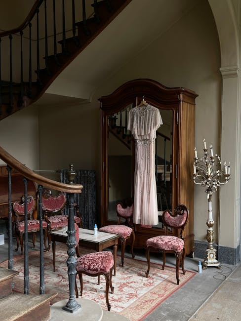Interior of a room with a wooden dining table and chairs, featuring floral upholstered seats. The floor is made of polished wooden planks, partially covered by a patterned rug. In the background, there is an arched doorway with a black metal gate, and a display stand holding various photographs or postcards. The room is well-lit with natural light, and the walls are painted in a light, neutral color. Carpet Cleaning Marylebone offers surface cleaning and deep upholstery sanitisation, maintaining the cleanliness and hygiene of domestic and commercial spaces such as this one.